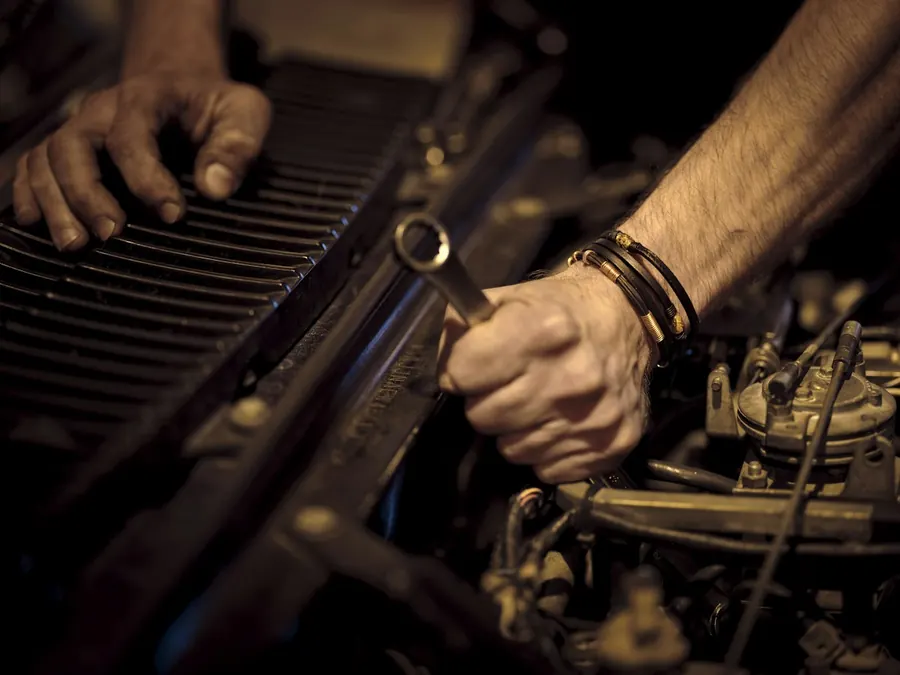 Hands working on an engine with a spanner